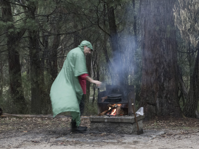 Doug tends the fire in the rain