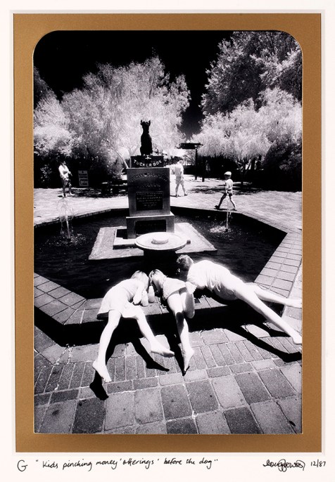 G  Gundagai – Five miles from Gundagai  is the location described in the bush verse about a bullocky’s bad luck. While the popular version of this story makes a hero of the bullocky’s dog who ‘sat on’ his tucker box protecting it from harm. However anyone reading the original poem would come to the conclusion – the ultimate in bad luck was that the dog ‘shat in’ the tucker box. In this image of the tourist memorial near Gundagai a statue of the dog ‘sits’ on the tucker box while kids steal money from the wishing fountain in front. Hume Highway near Gundagai, New South Wales.